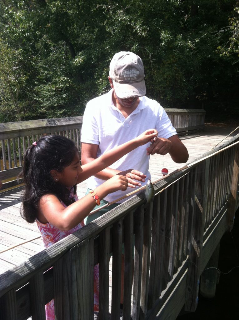 A new angler gets a little help taking her first fish off the line.